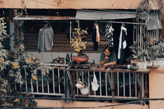 A woman on a balcony with plants and laundry in Ho Chi Minh City, Vietnam.
