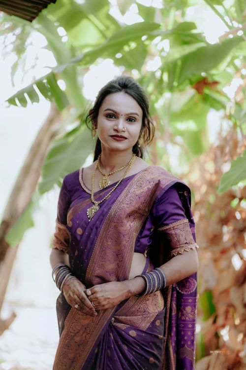 Free A woman in a purple sari poses gracefully outdoors, surrounded by lush greenery. Stock Photo