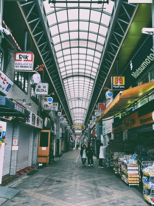 Free Street shot of a lively indoor market in Japan with people walking, colorful signs, and shops. Stock Photo