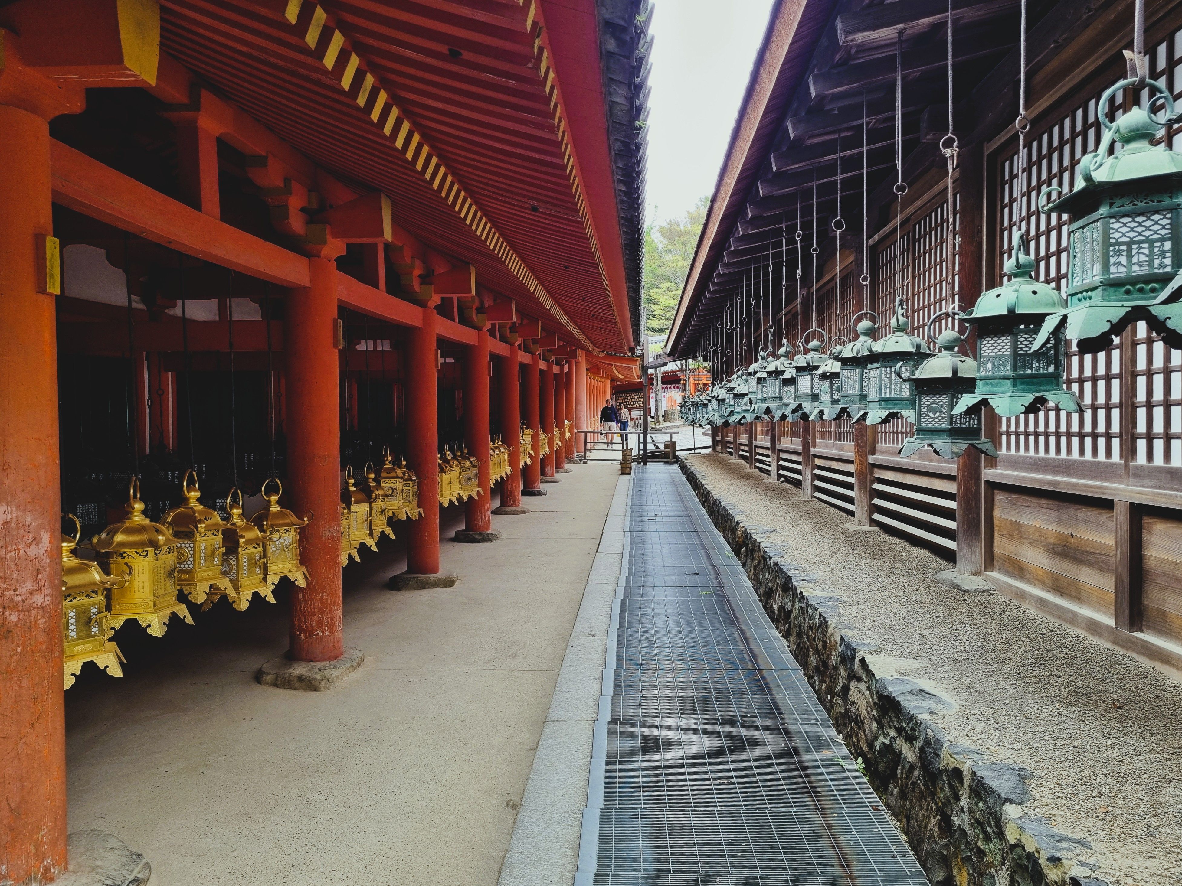 Kasuga Taisha's vermilion corridor lined with hundreds of bronze lanterns glowing at dusk in Nara
