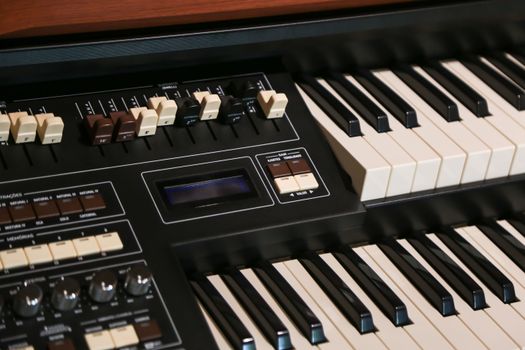 Close-up image of a vintage electric organ keyboard with control panel, featuring keys and drawbars.