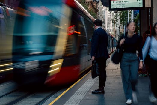 Blur of people and train at a Sydney light rail station capturing city life and motion.