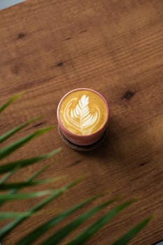 Elegant latte art captured from above on a rustic wooden table.