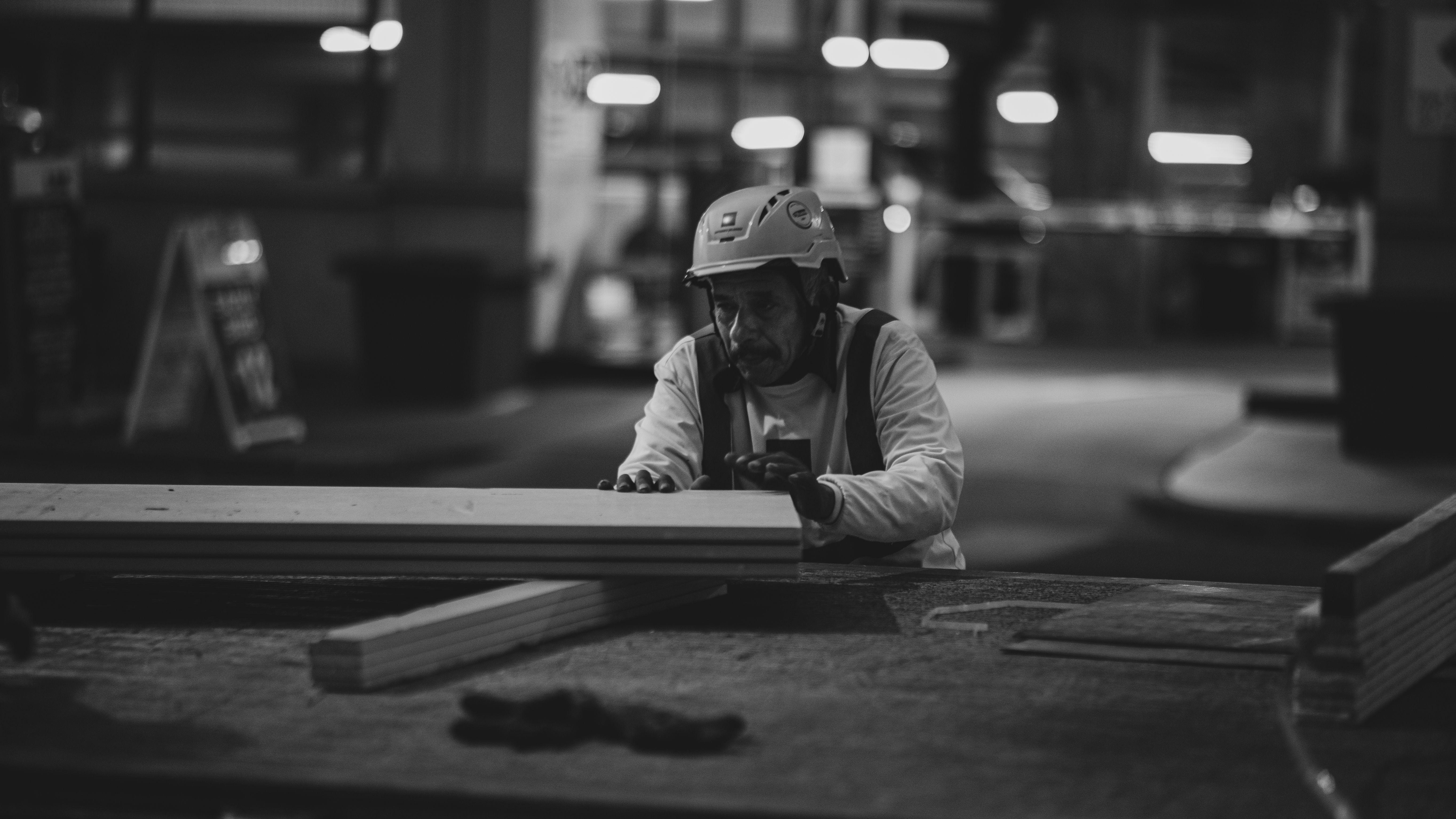 Black and white photo of a construction worker focusing on woodwork in Houston at night.