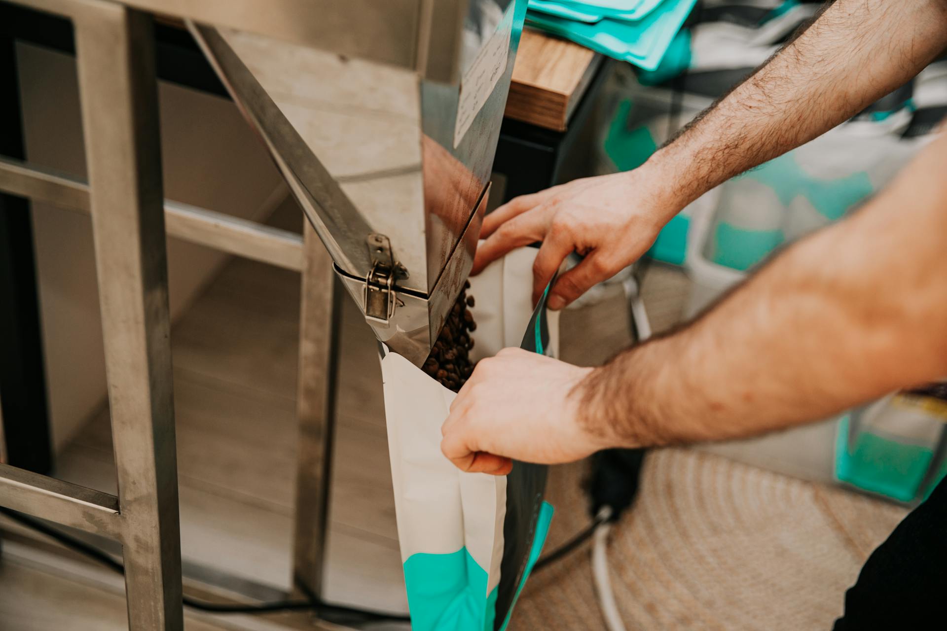 Hands packaging coffee beans in a modern industrial facility.