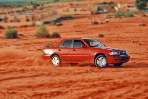 Free A red car skillfully drifts across the vibrant red sands of the desert. Stock Photo