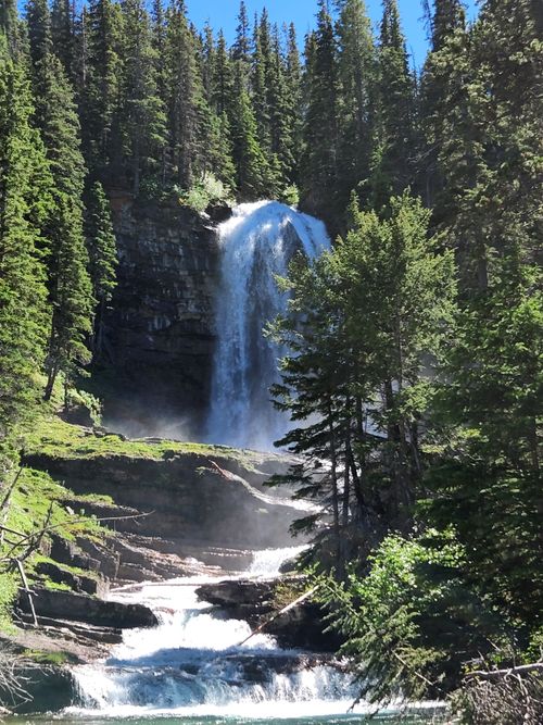 Free Breathtaking waterfall cascading in a lush green forest, illuminated by sunlight. Stock Photo