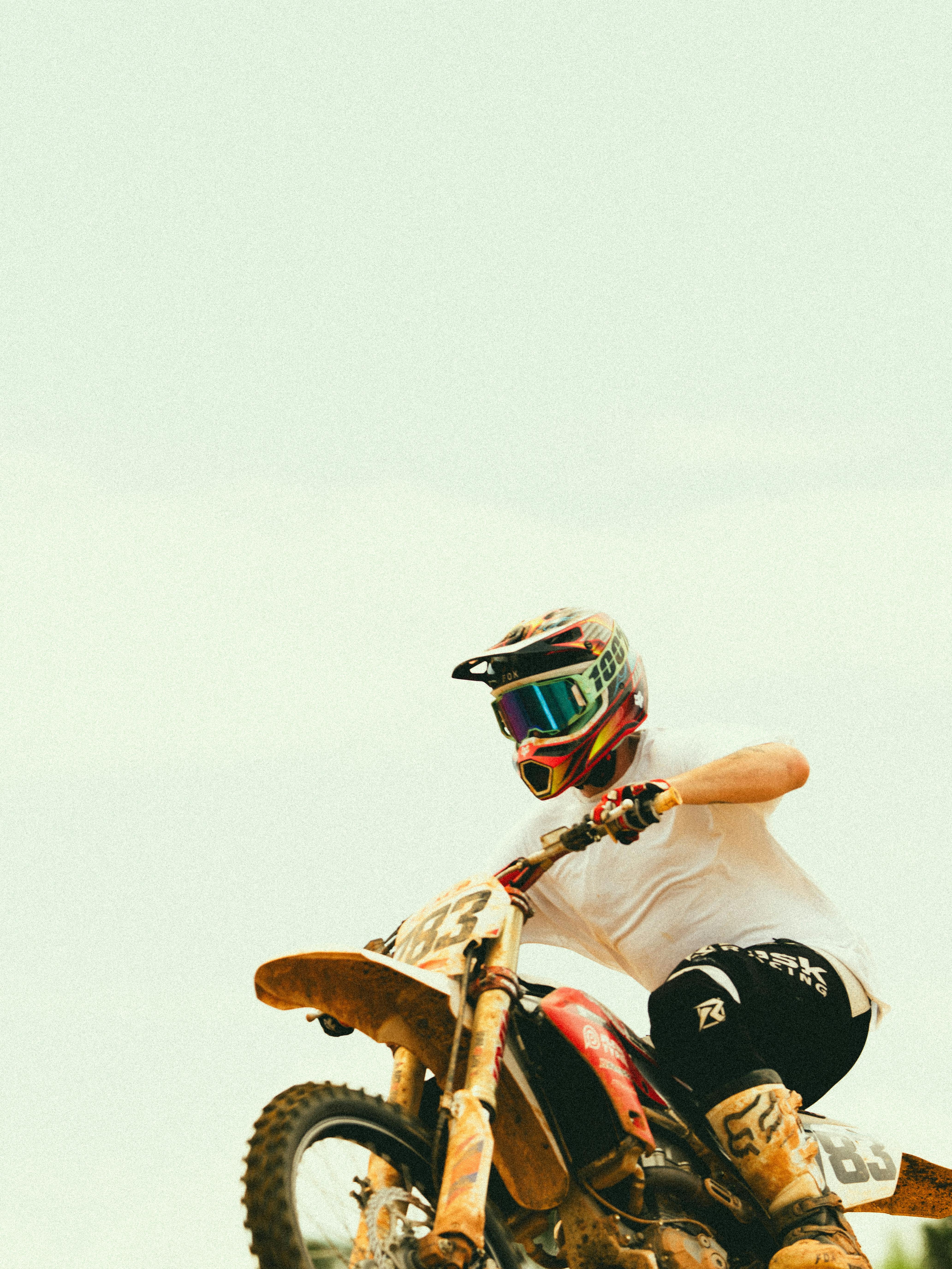 Motocross rider performing a stunt on a dirt bike under clear skies, showcasing speed and skill.