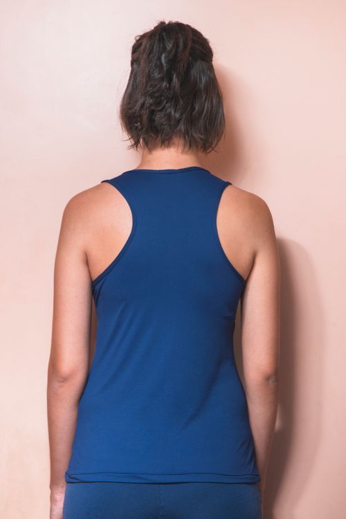 Free A person with short hair in a blue tank top captured from behind, standing against a peach wall. Stock Photo