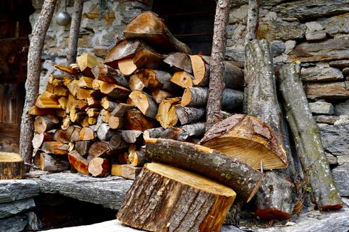 Free A stack of chopped firewood against a rustic stone wall, embodying a cozy autumn feel. Stock Photo