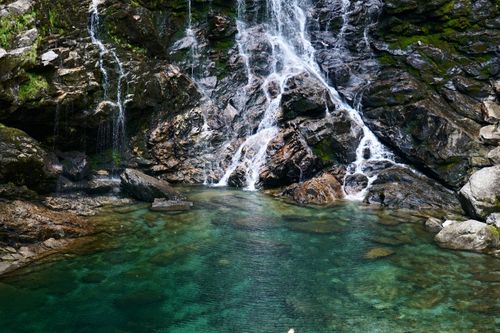 Free A tranquil waterfall cascades into a pristine pool surrounded by lush rocks. Stock Photo