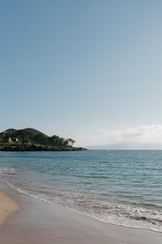 Serene beach scene in Hawaii showcasing pristine waters and clear skies; ideal for travel inspiration.