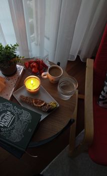 Warm, inviting morning with coffee, candlelight, pastries, and strawberries on a wooden table.