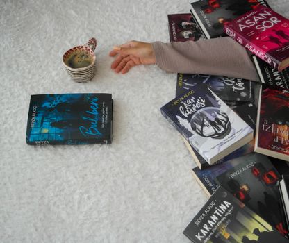 A warm setting featuring an arm amidst books and a cup of tea, ideal for book lovers.