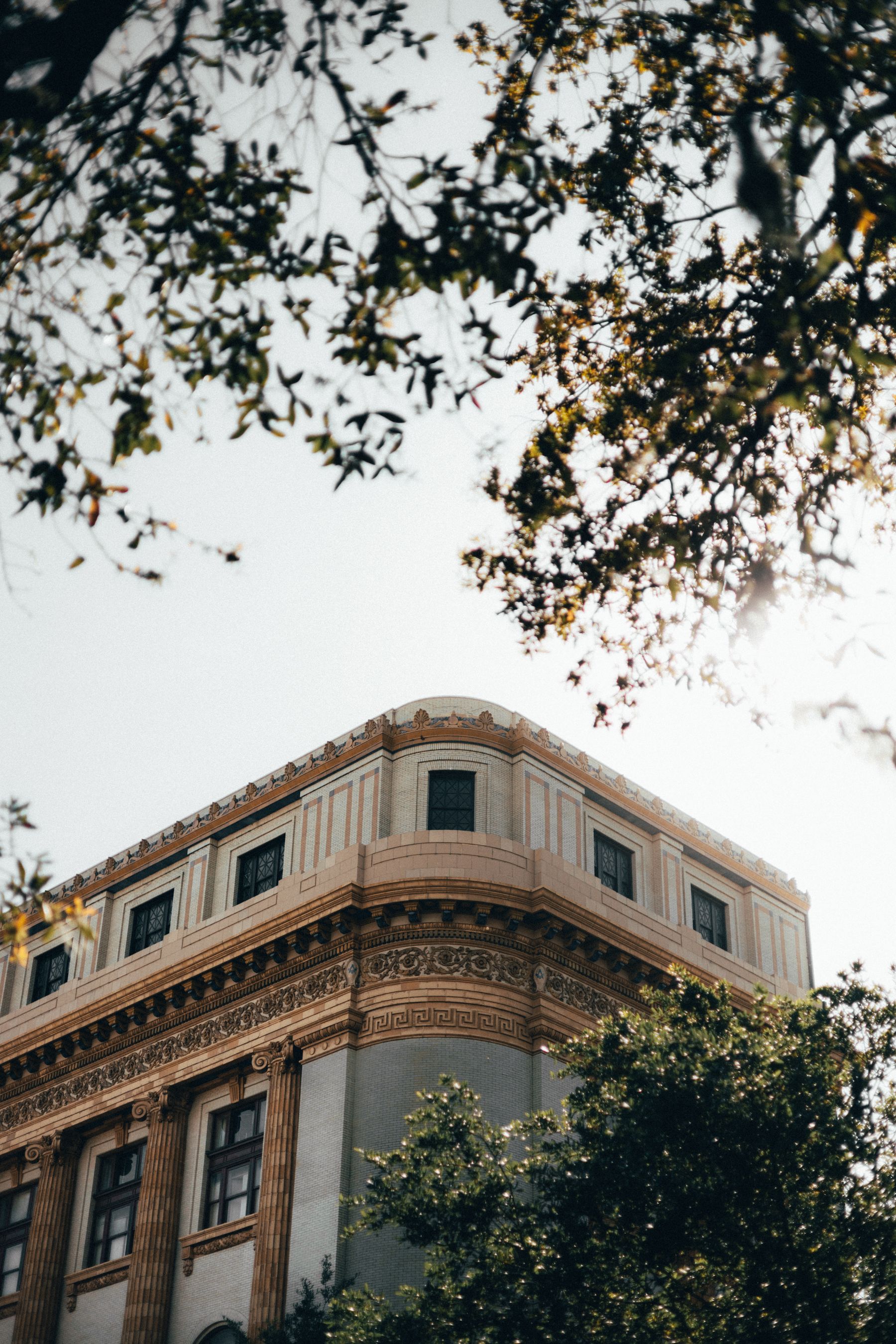 High-angle view of an ornate historic building framed by trees in Savannah, Georgia.