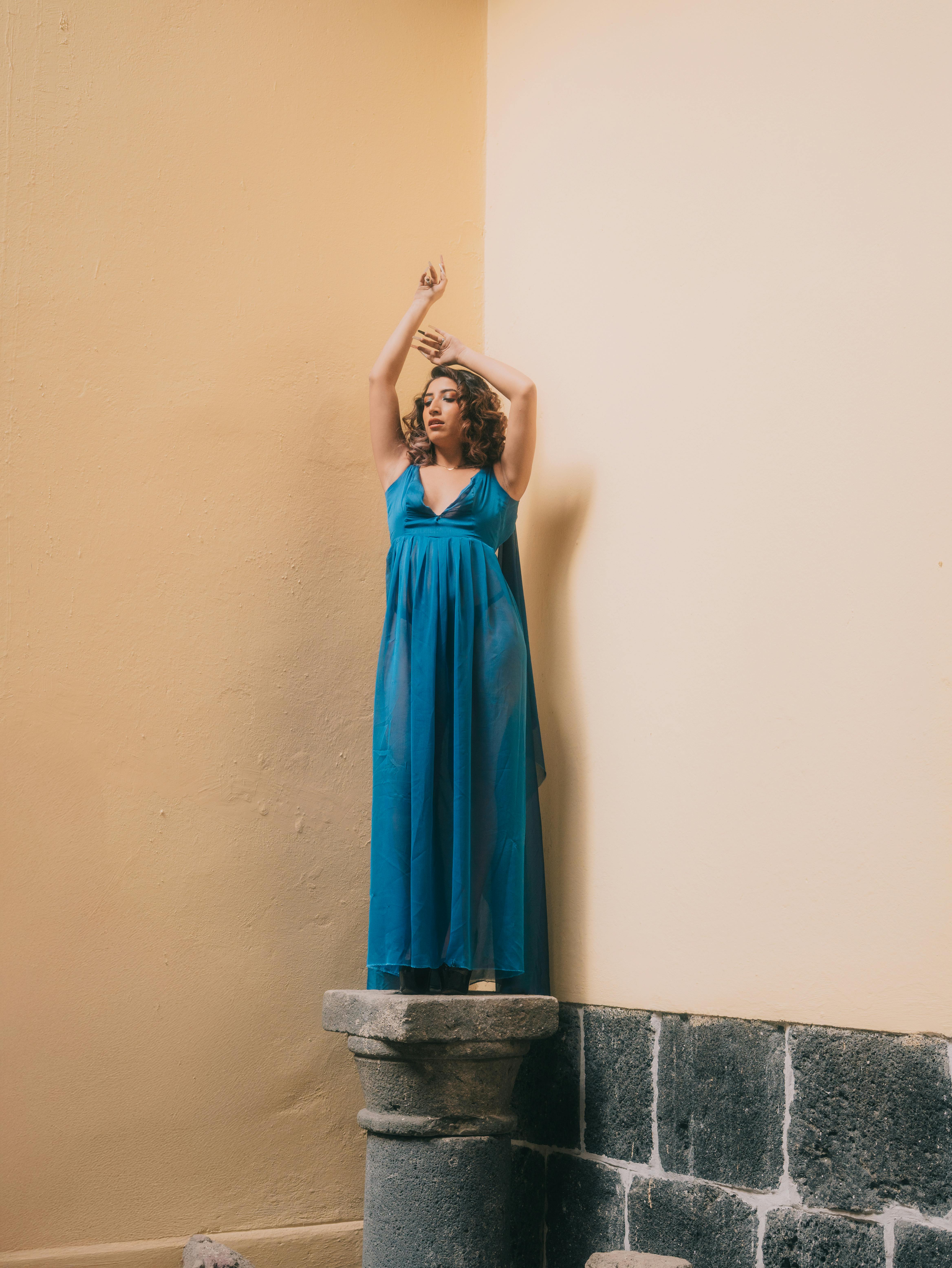 grátis Modelo de vestido azul posando elegantemente em uma coluna na Cidade do México. Foto profissional