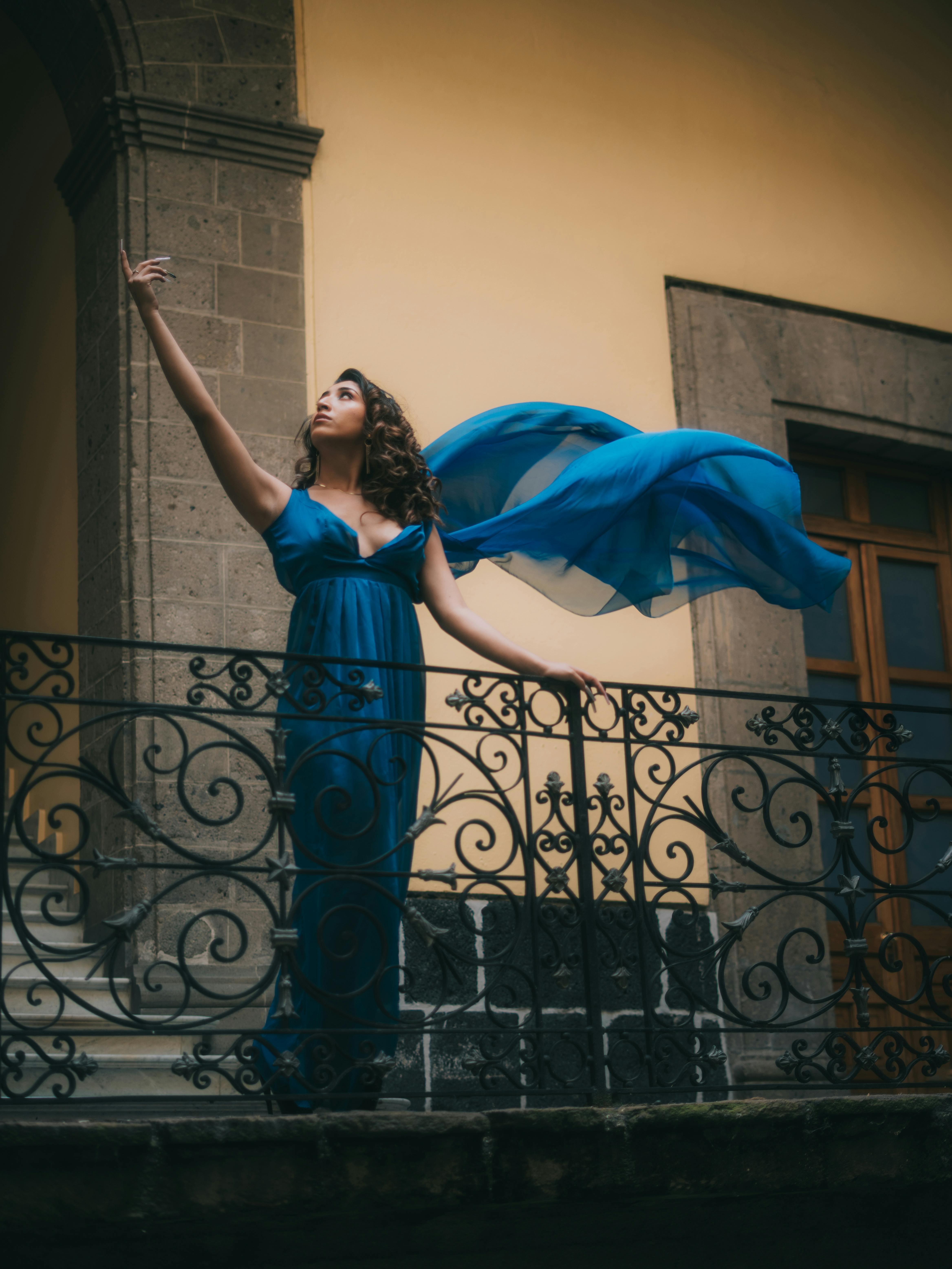 Gratuit O femeie într-o rochie albastră face o ipostază grațioasă pe un balcon istoric. Fotografie de stoc