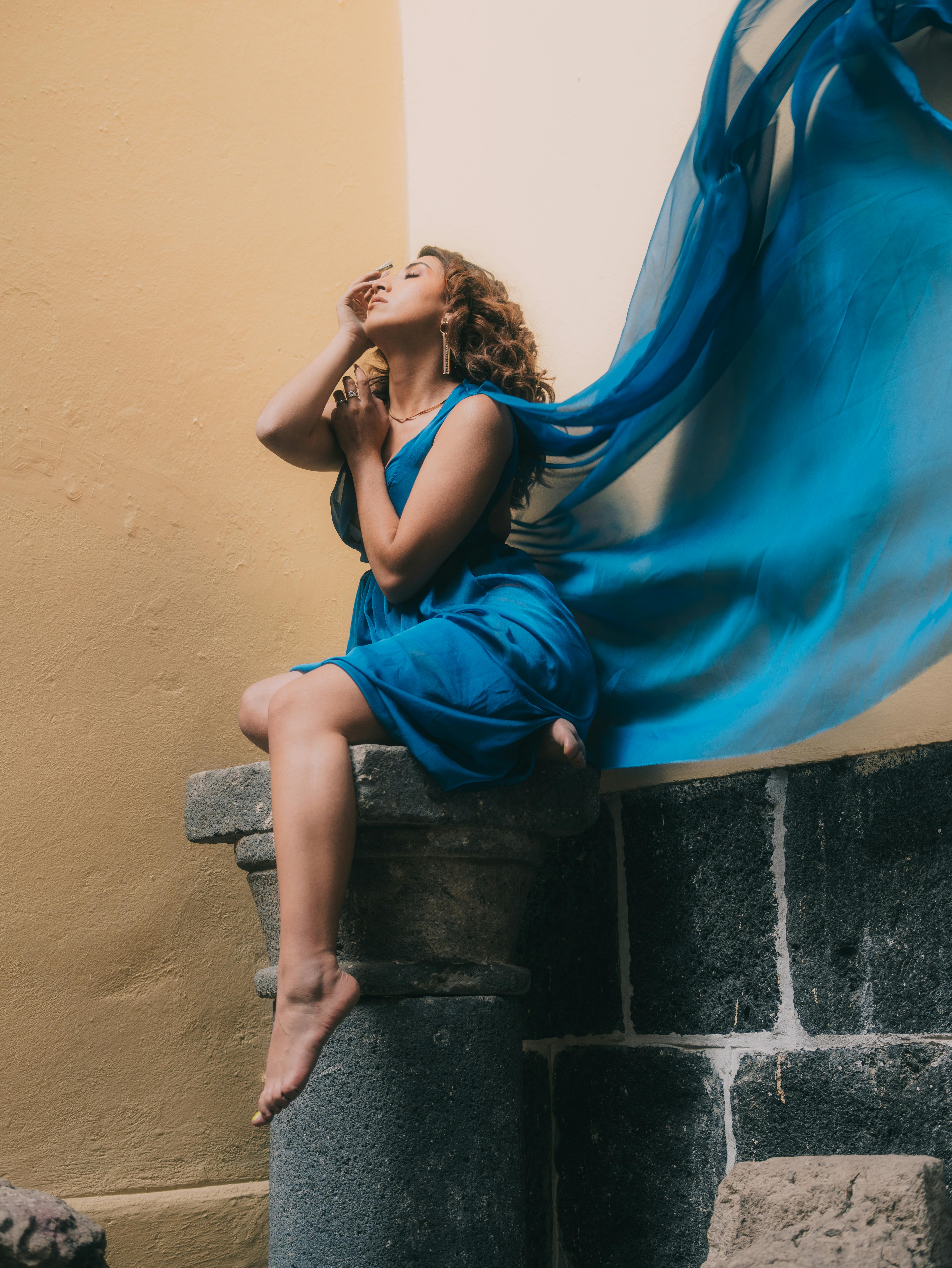 De franc Model de moda amb un vestit blau fluid, posant sobre un pedestal de pedra a Ciutat de Mèxic. Foto d'estoc