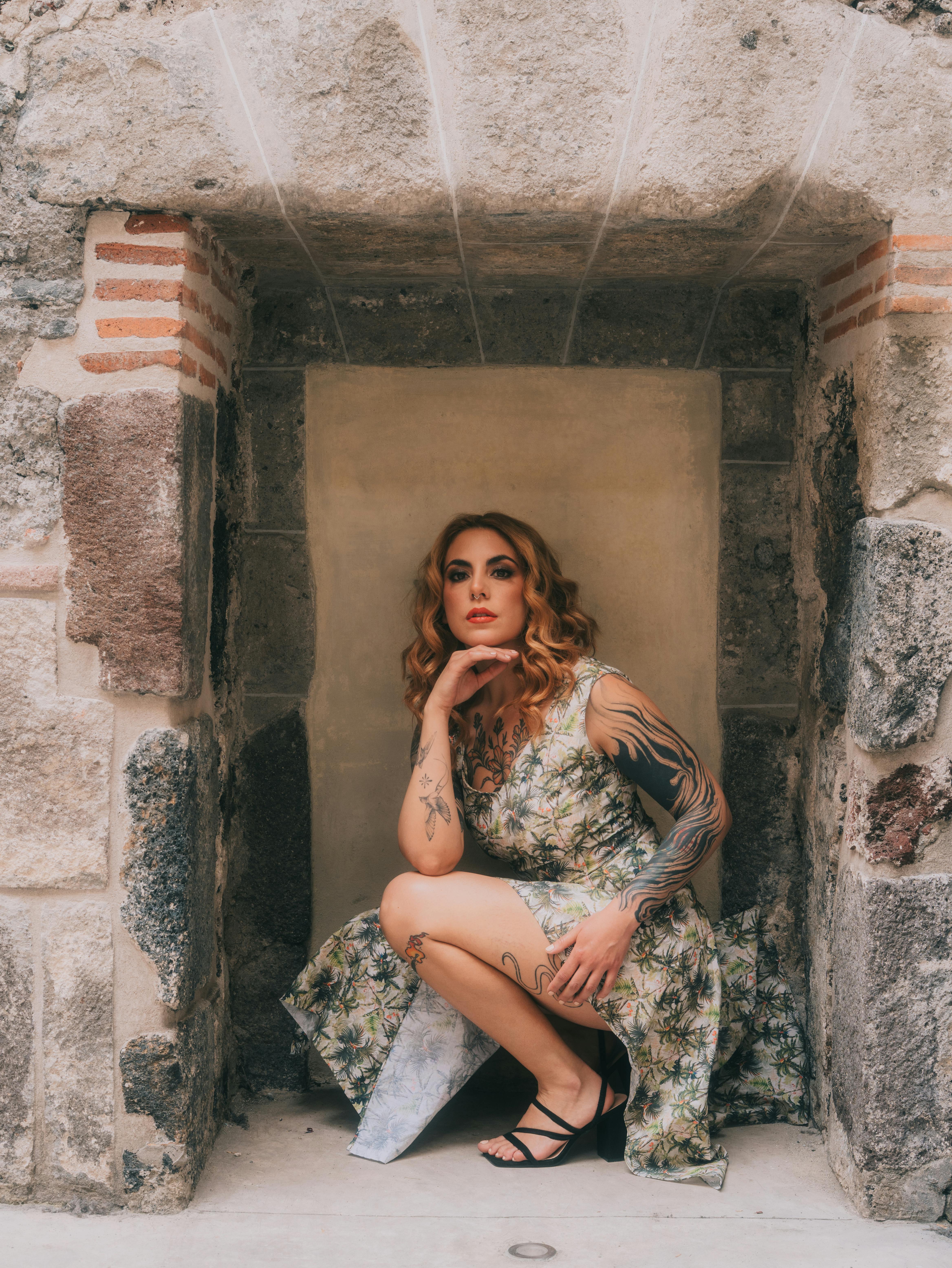 gratis Een stijlvolle vrouw in een bloemenjurk poseert bij een historische stenen muur in Mexico-Stad. Stockfoto