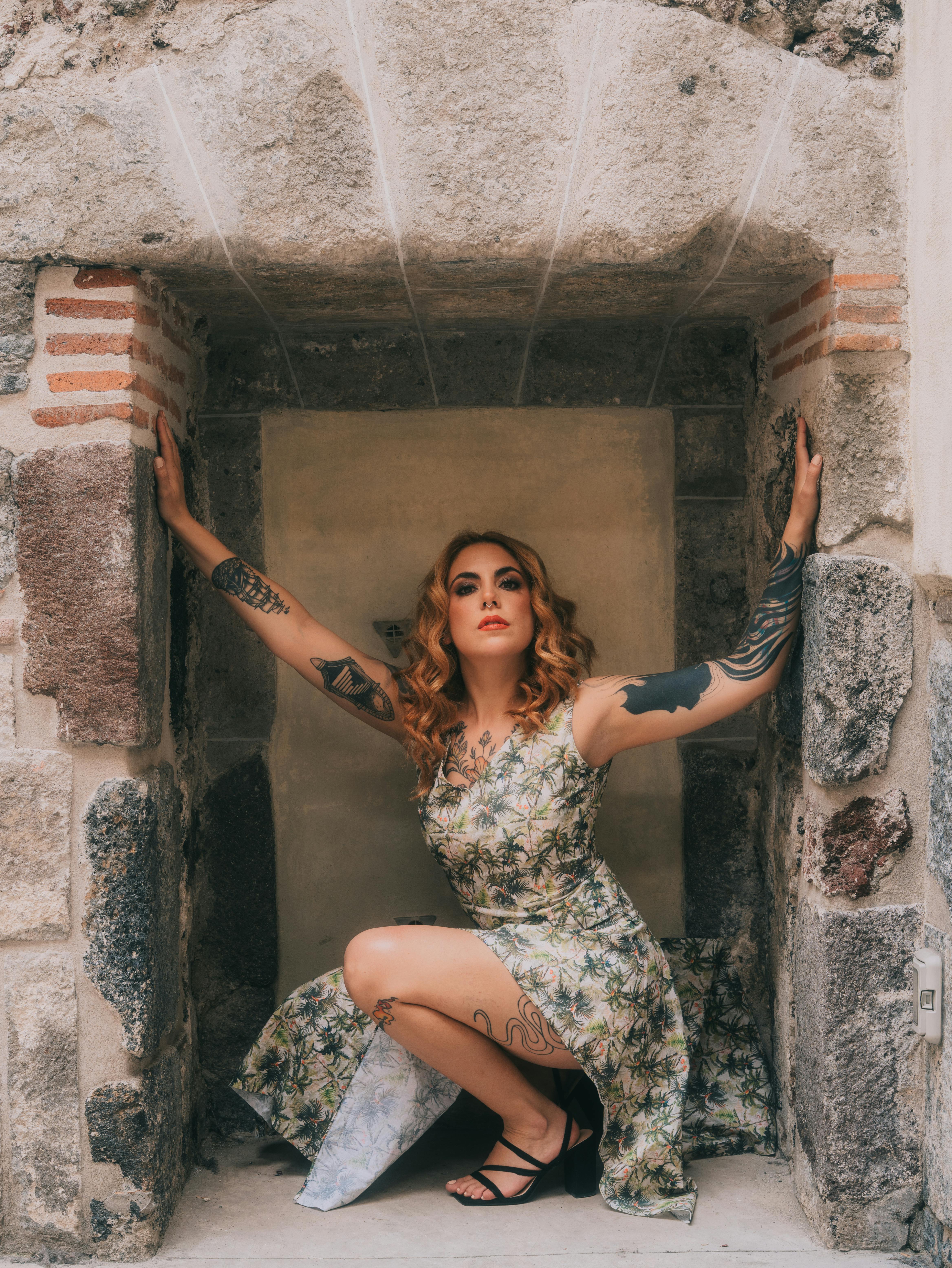 Gratuit Portrait élégant d'une femme tatouée en tenue florale sur fond de pierre rustique. Photos