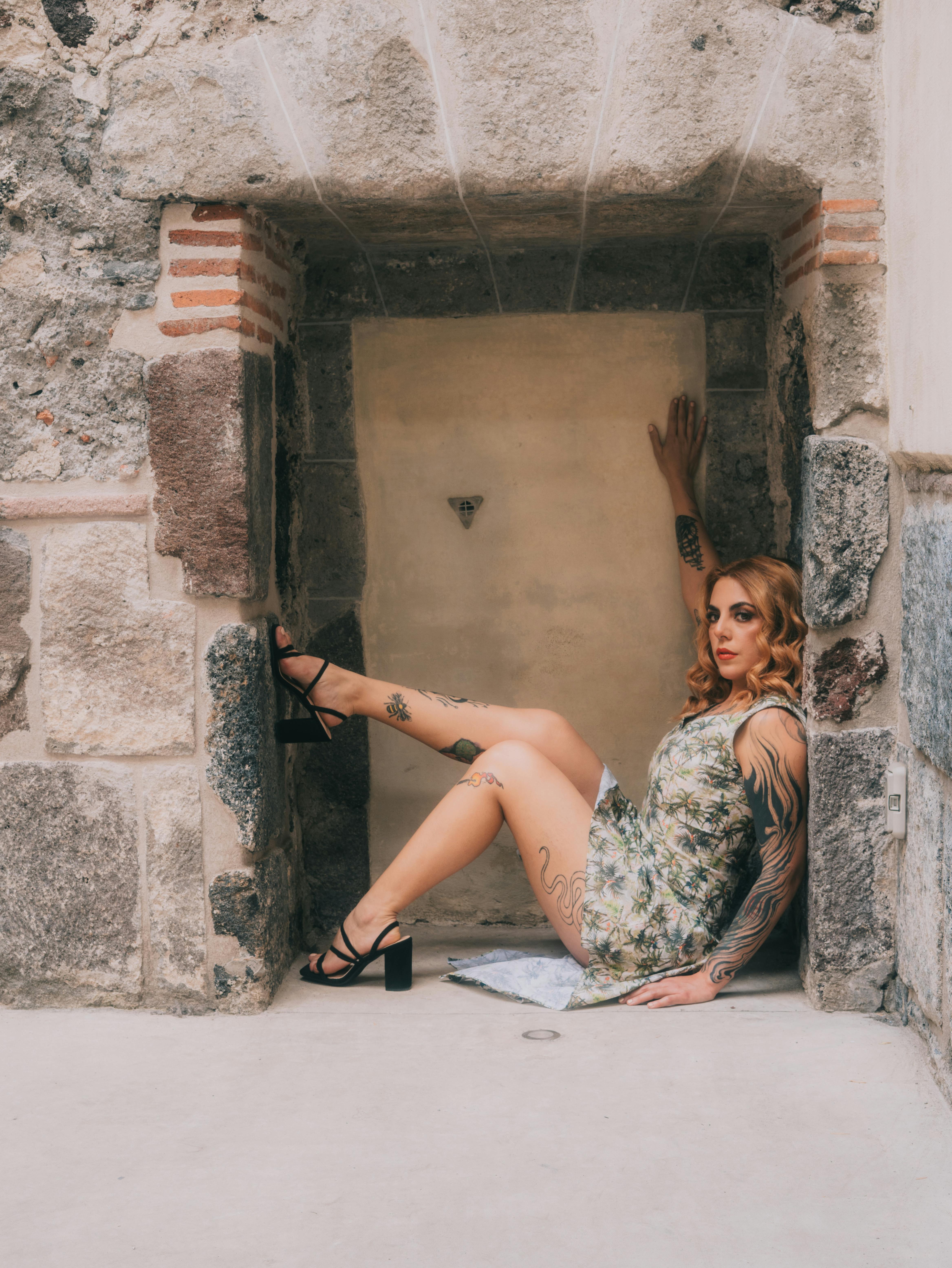 Free Fashion model in a floral dress poses elegantly in a historic stone setting. Stock Photo