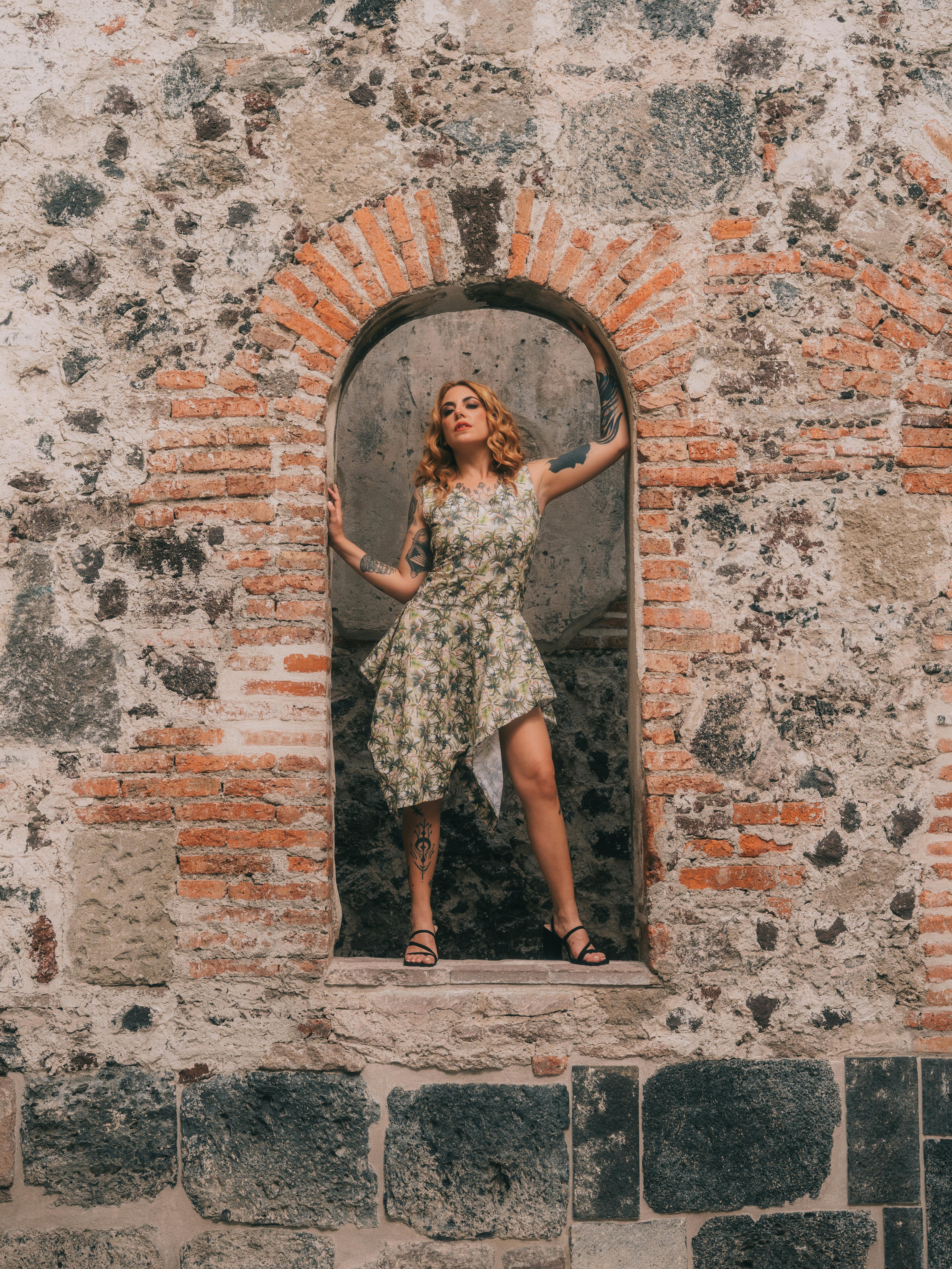 Gratis Una donna alla moda posa sotto uno storico arco in pietra a Città del Messico, mettendo in risalto il suo elegante stile estivo. Foto a disposizione