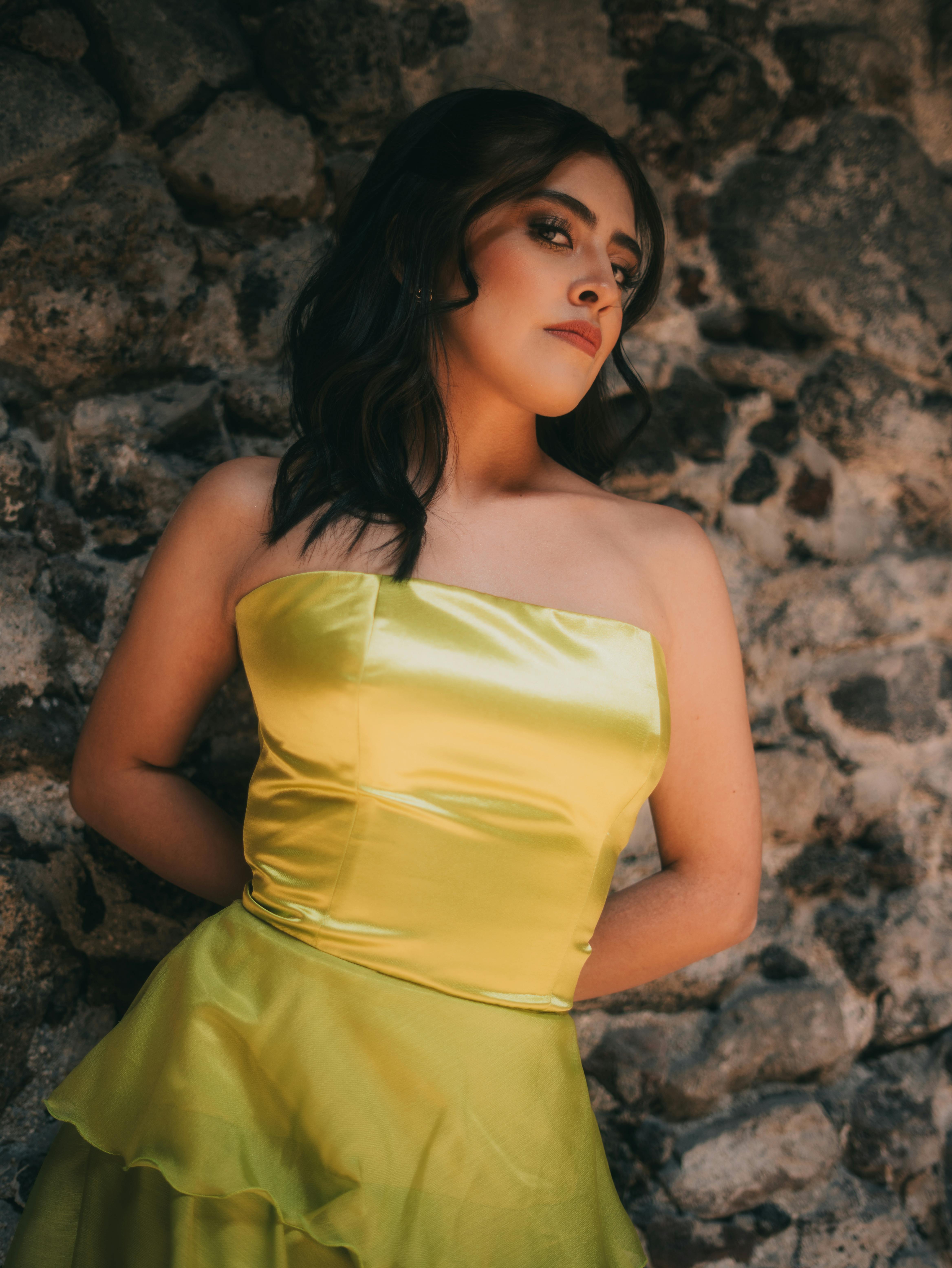 Free Stylish woman in elegant dress posing against stone wall in Mexico City Stock Photo