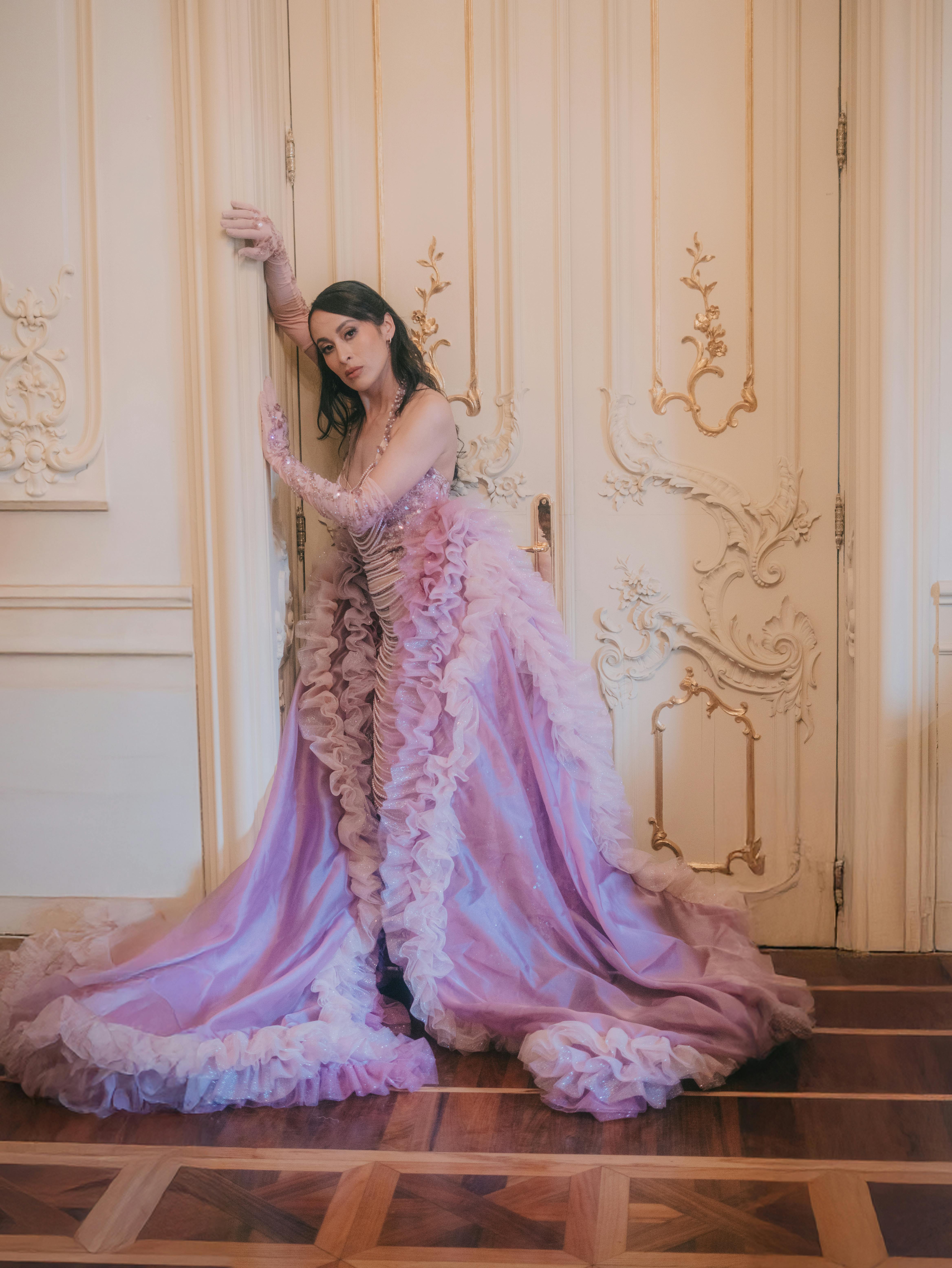 Kostenlos Fashionmodel in einem luxuriösen rosa Kleid posiert elegant im Innenbereich. Stock-Foto