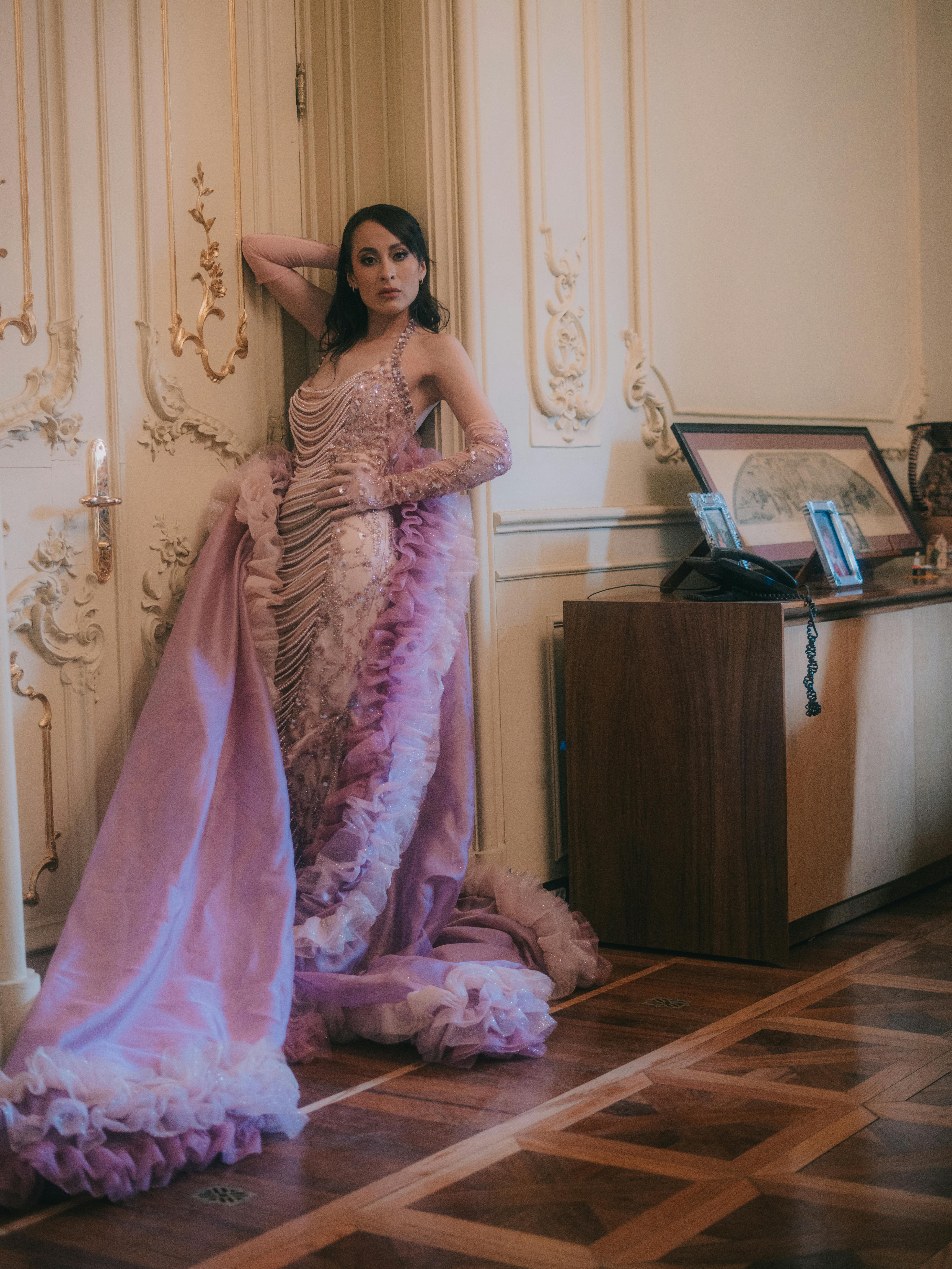 Zadarmo Žena pózuje v luxusnej róbe opretá o zdobené dvere v bohato zdobenej miestnosti. Fotka z fotobanky