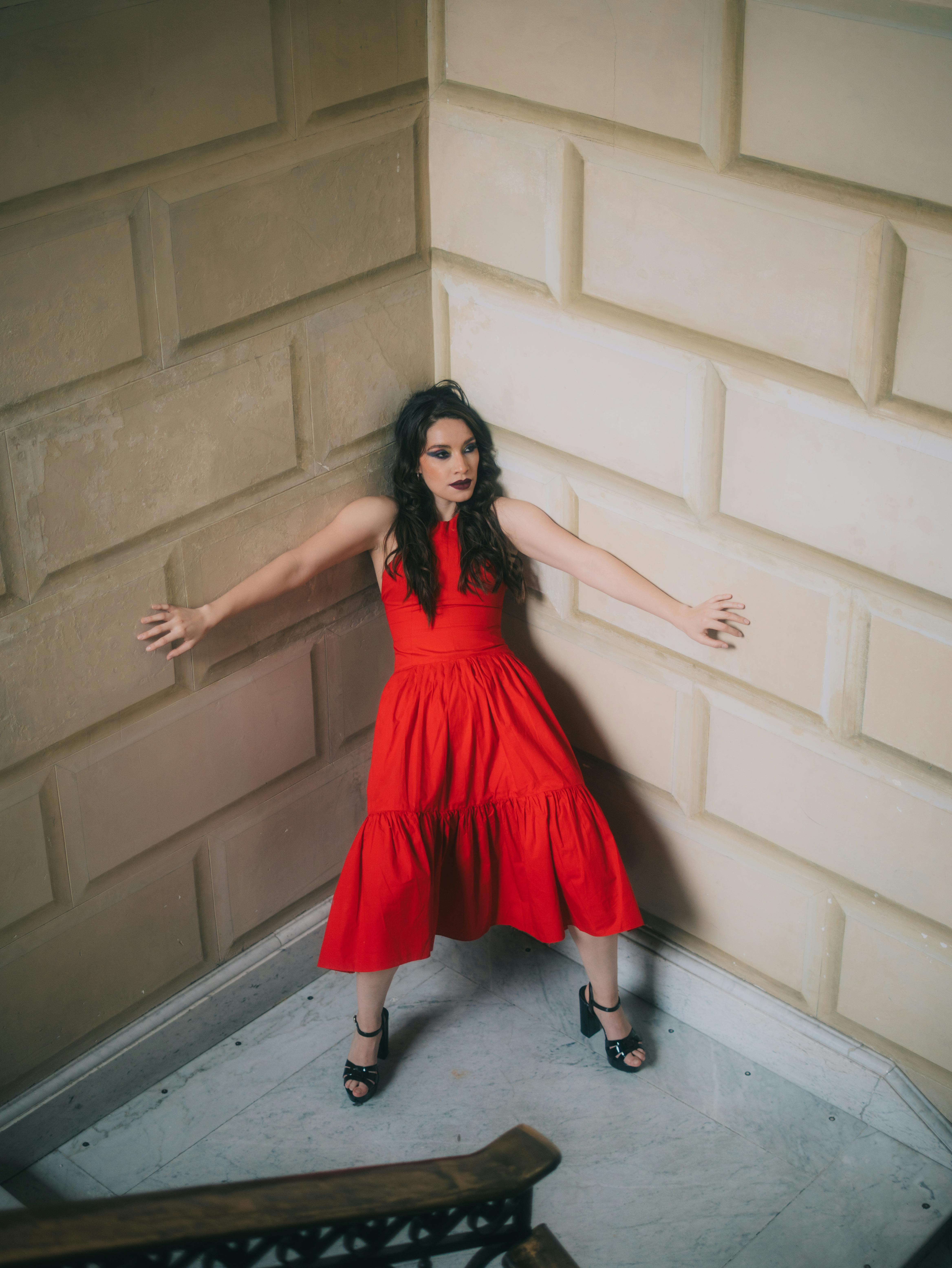 Free Elegant woman in a striking red dress posing stylishly in a museum setting. Stock Photo