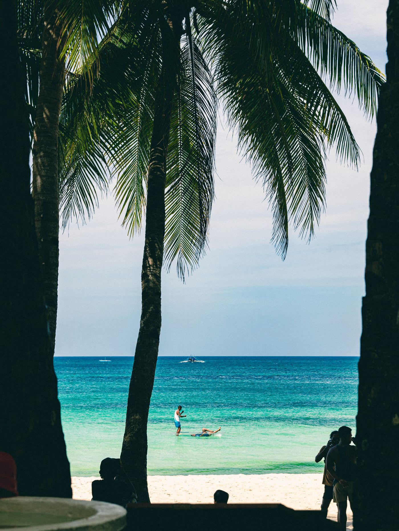 Coconut palm trees framing the blue sea on a white-sand beach in Boracay, Philippines