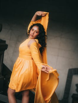 A stylish woman posing in a vibrant yellow dress indoors.