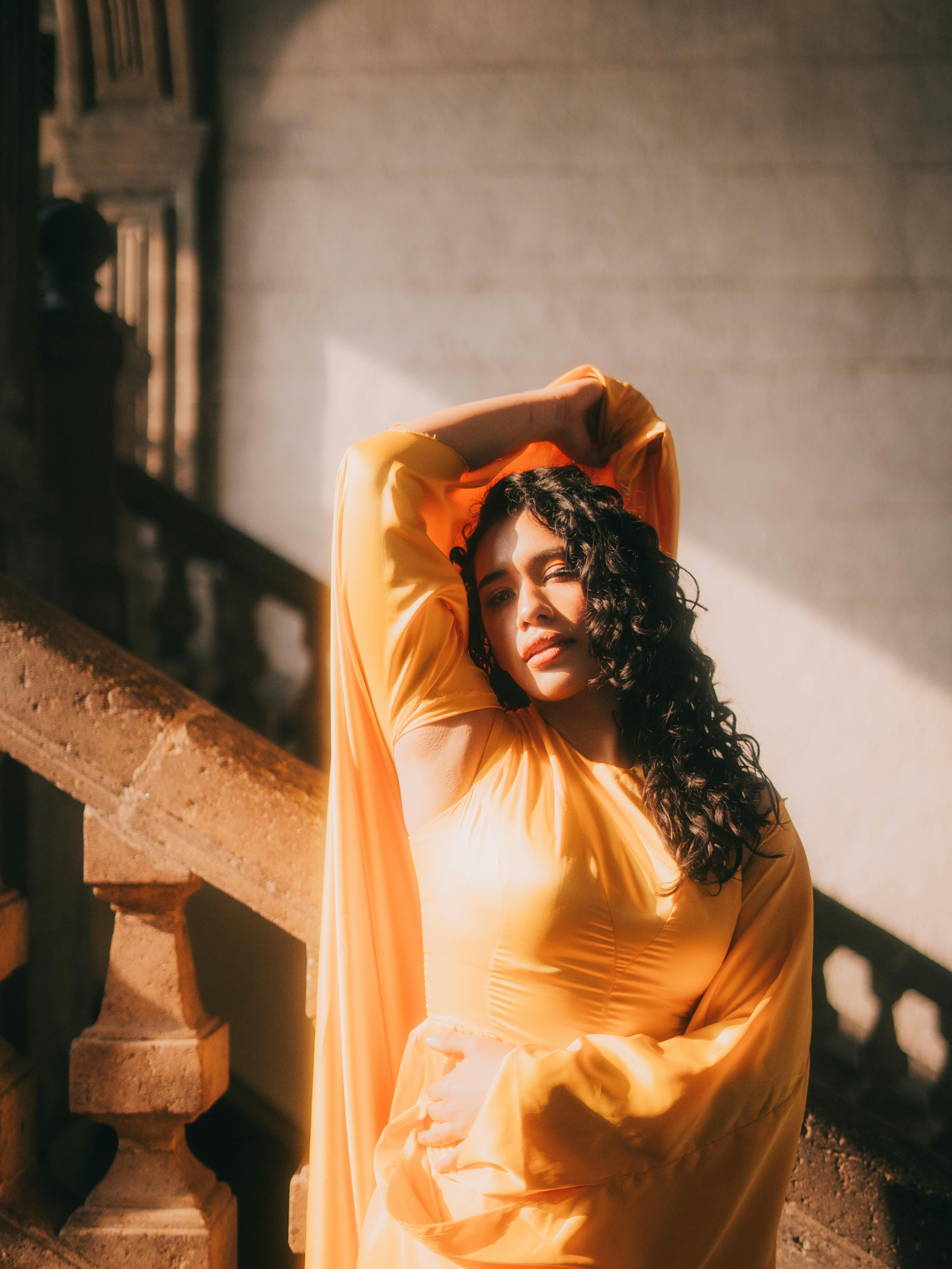 Gratis Potret mode seorang wanita dalam gaun kuning berpose anggun di tangga yang disinari matahari di Mexico City. Foto Stok