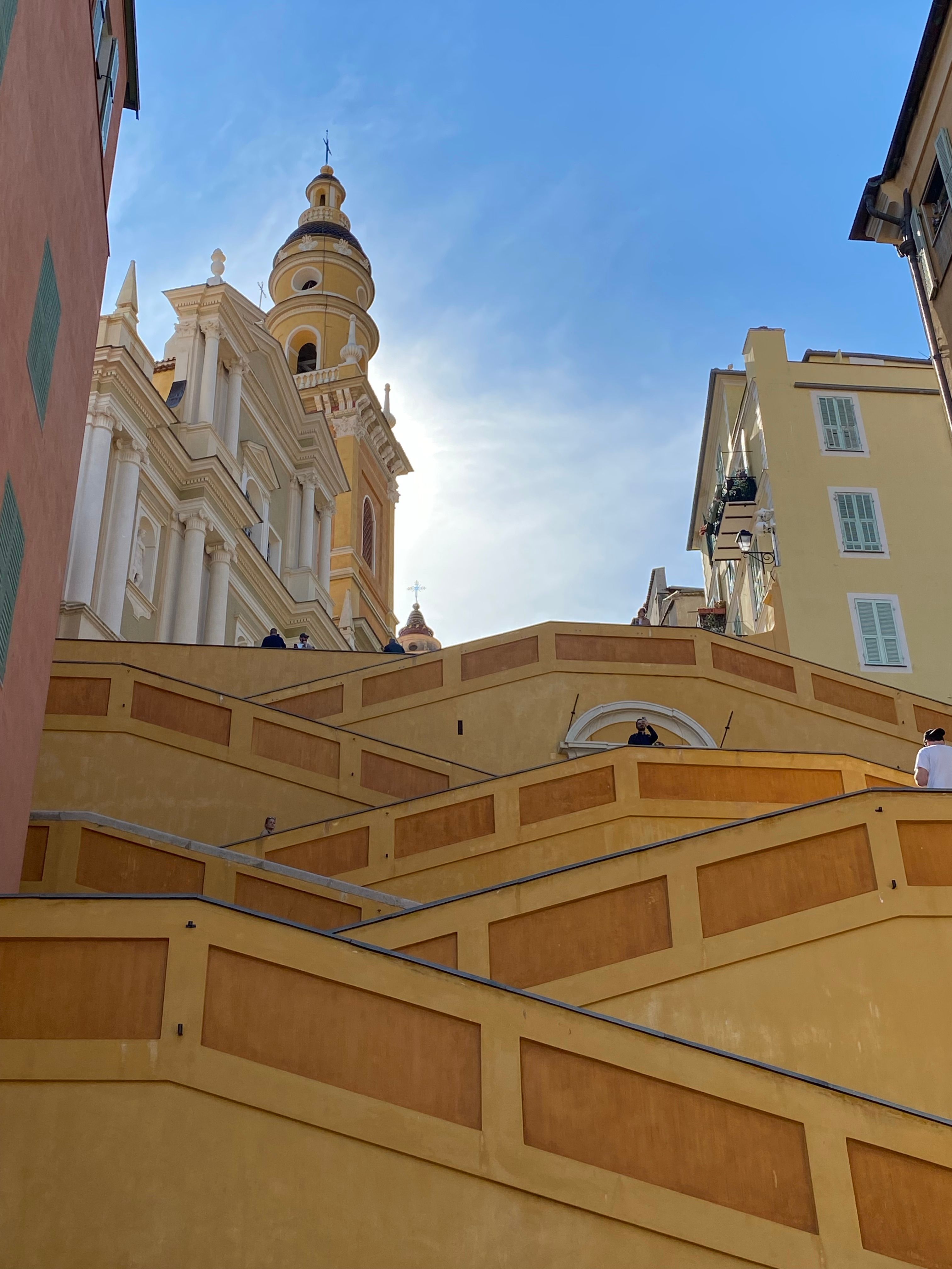 View of a historic church with intricate stairs leading to it in Menton, France.