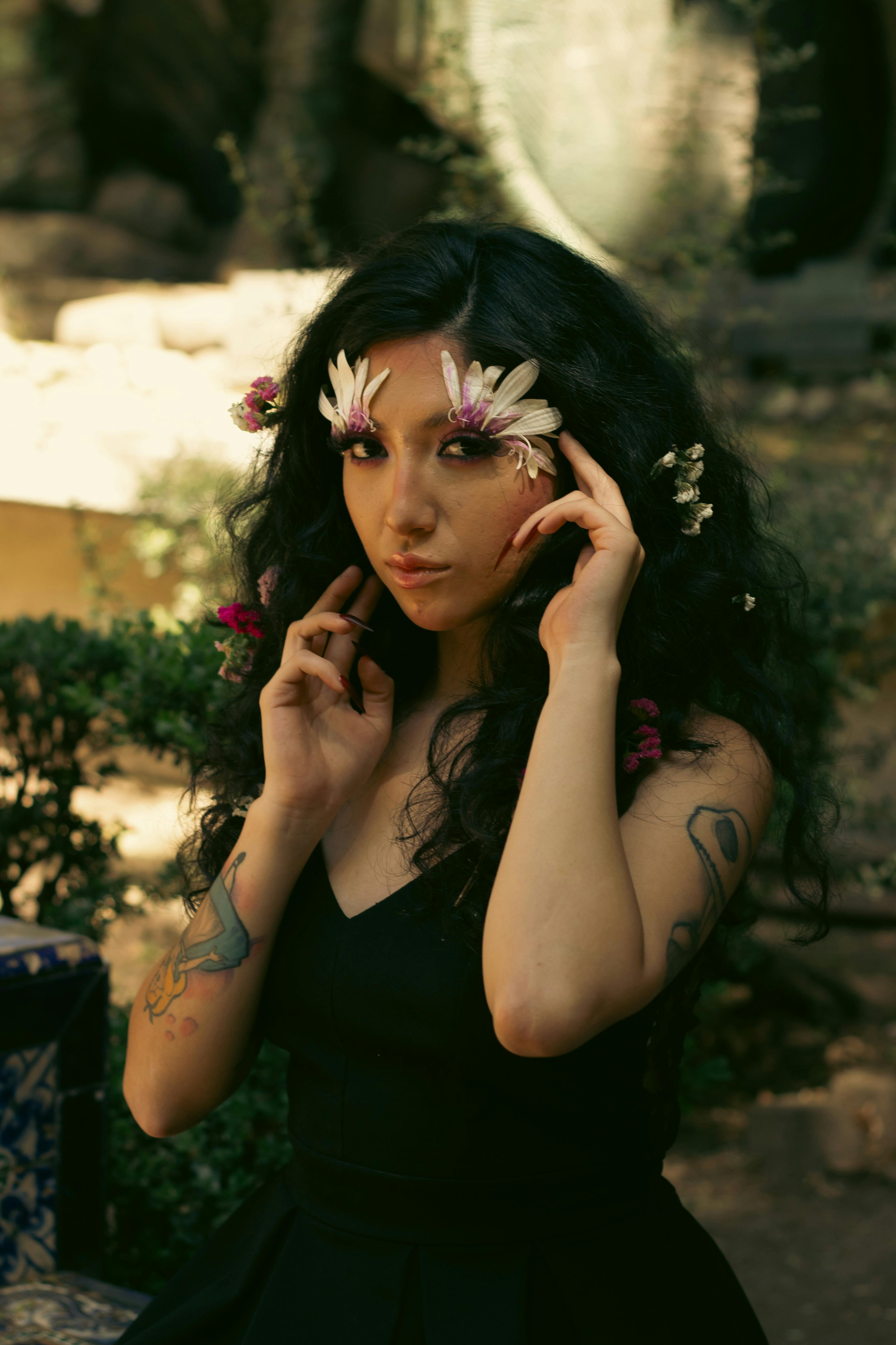 bezplatná Žena s květinami ve vlasech elegantně pózuje venku s měkkým osvětlením. Základová fotografie