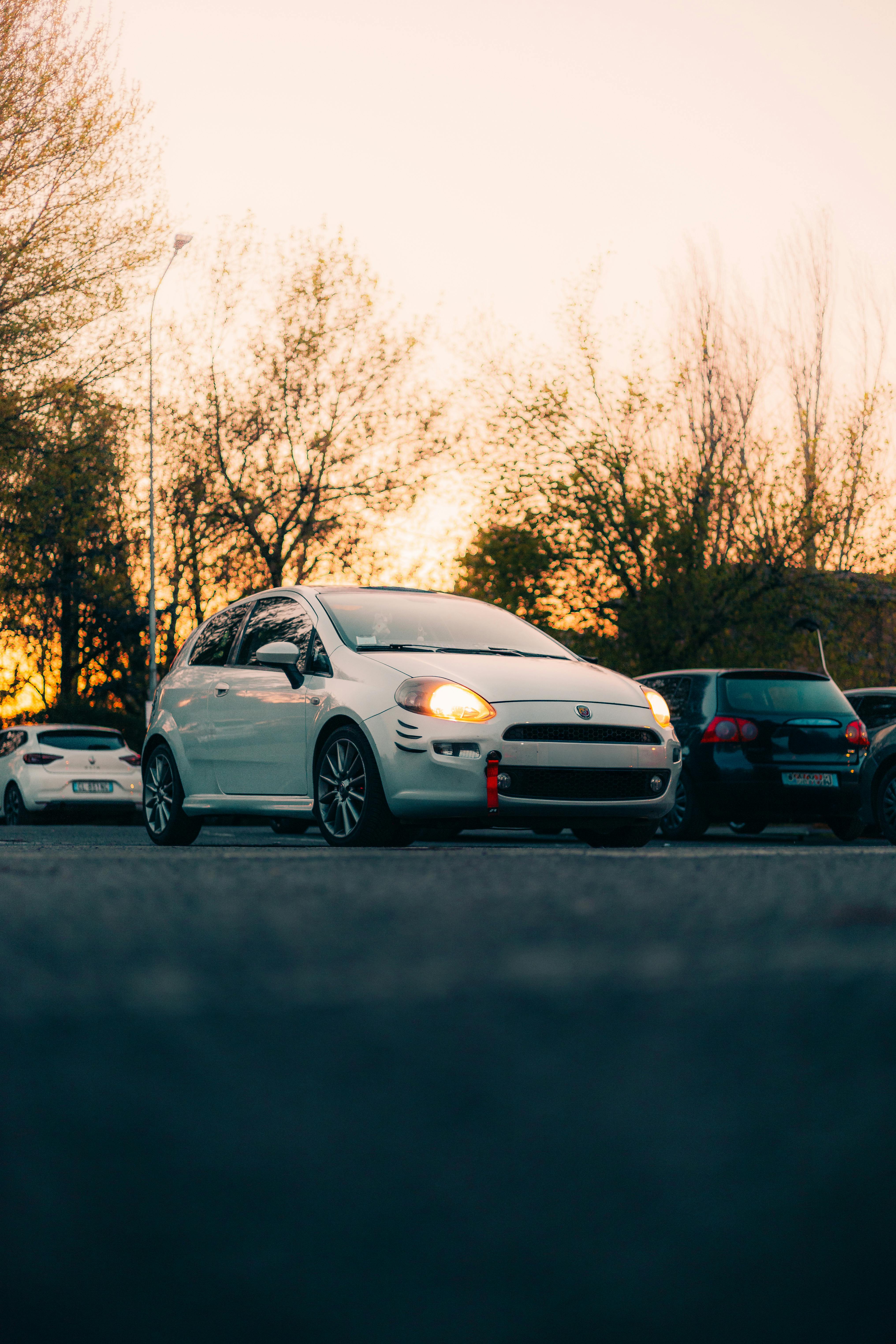Free Stylish white car parked under a beautiful sunset sky. Stock Photo