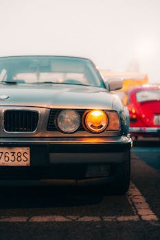 Front view of a classic car with headlights on at sunset with a retro vibe.