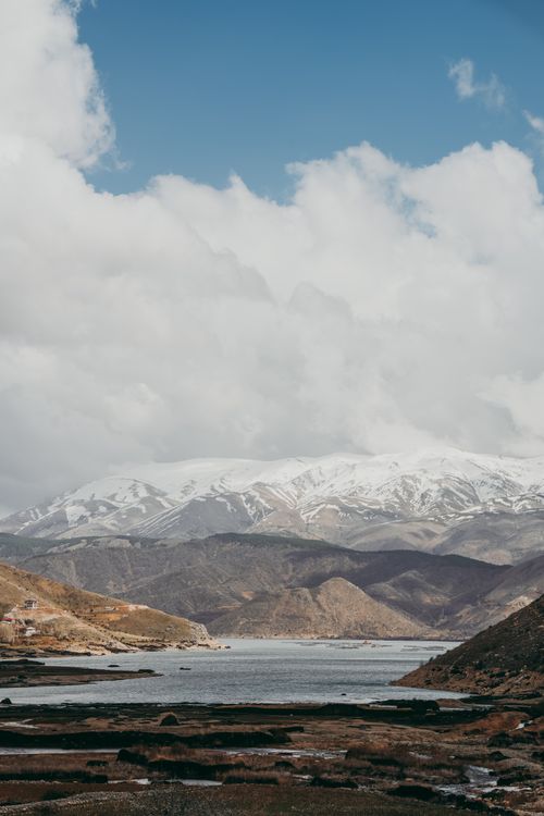 Free Tranquil scene of snow-capped mountains and a peaceful lake under a bright sky. Stock Photo