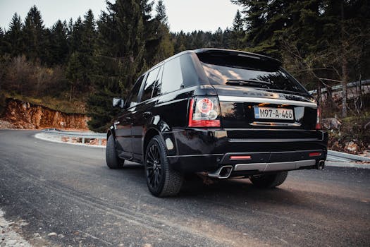 Elegant Range Rover on a winding Sarajevo road, capturing the essence of luxury and adventure at sunset.