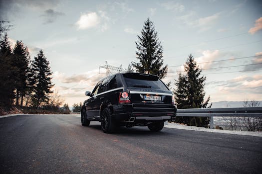 Elegant Range Rover SUV navigating a scenic highland road near Sarajevo at golden hour.
