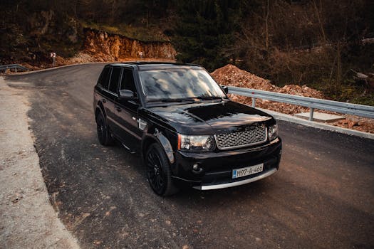 Black luxury SUV parked on a winding mountain road in Sarajevo, Bosnia.