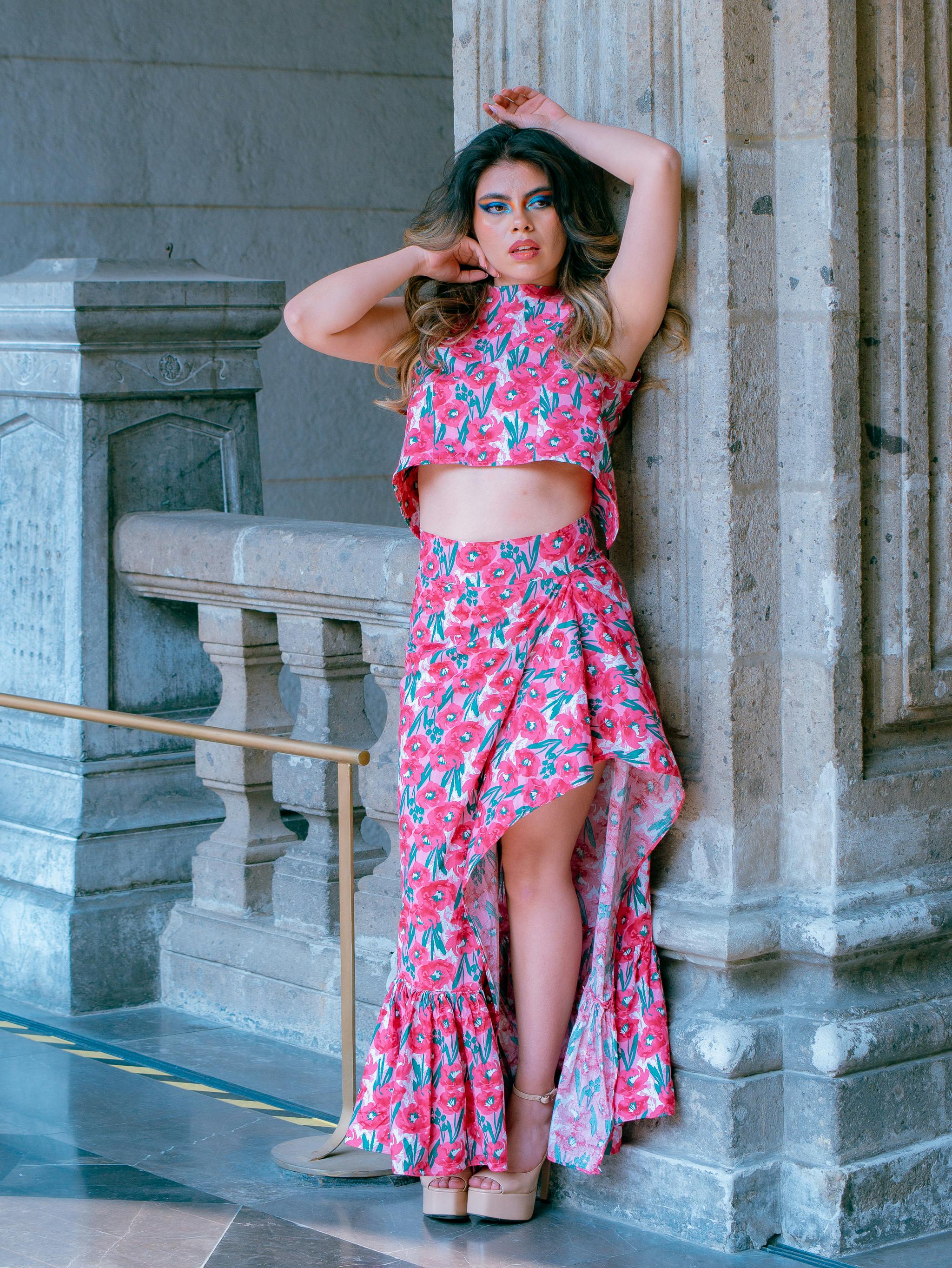Stylish model in floral dress posing against elegant stone architecture in Mexico City.
