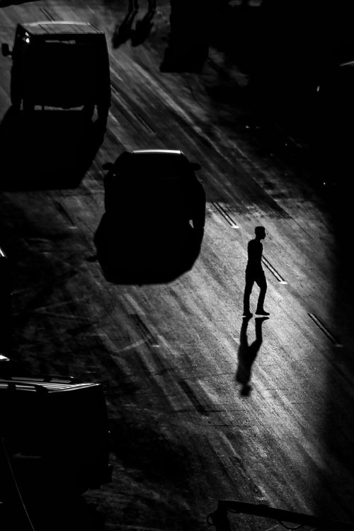 Free Dramatic black and white silhouette of a person walking on a street at night. Stock Photo