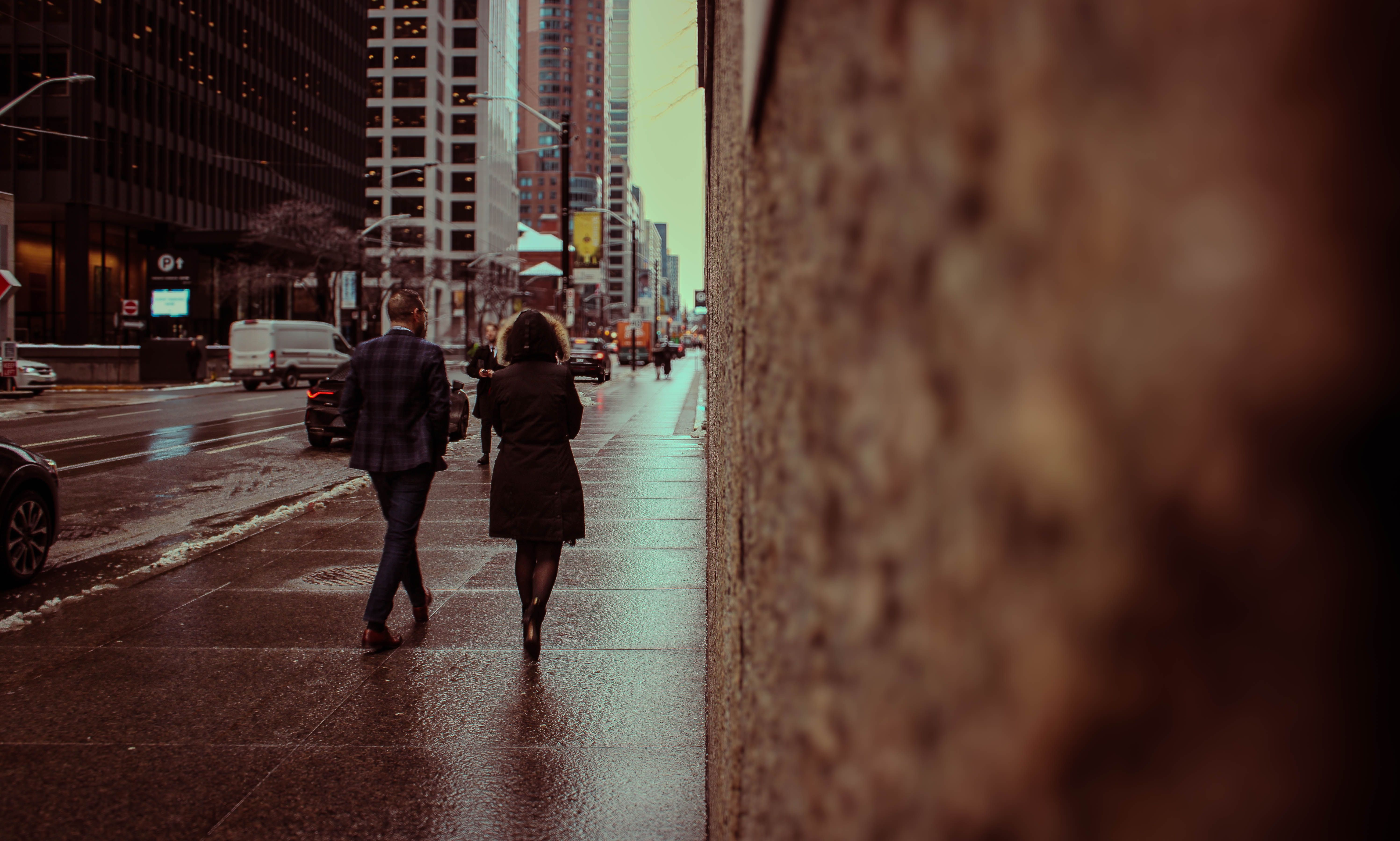 A couple walking on a wet sidewalk in downtown Toronto during winter, creating an urban atmosphere.