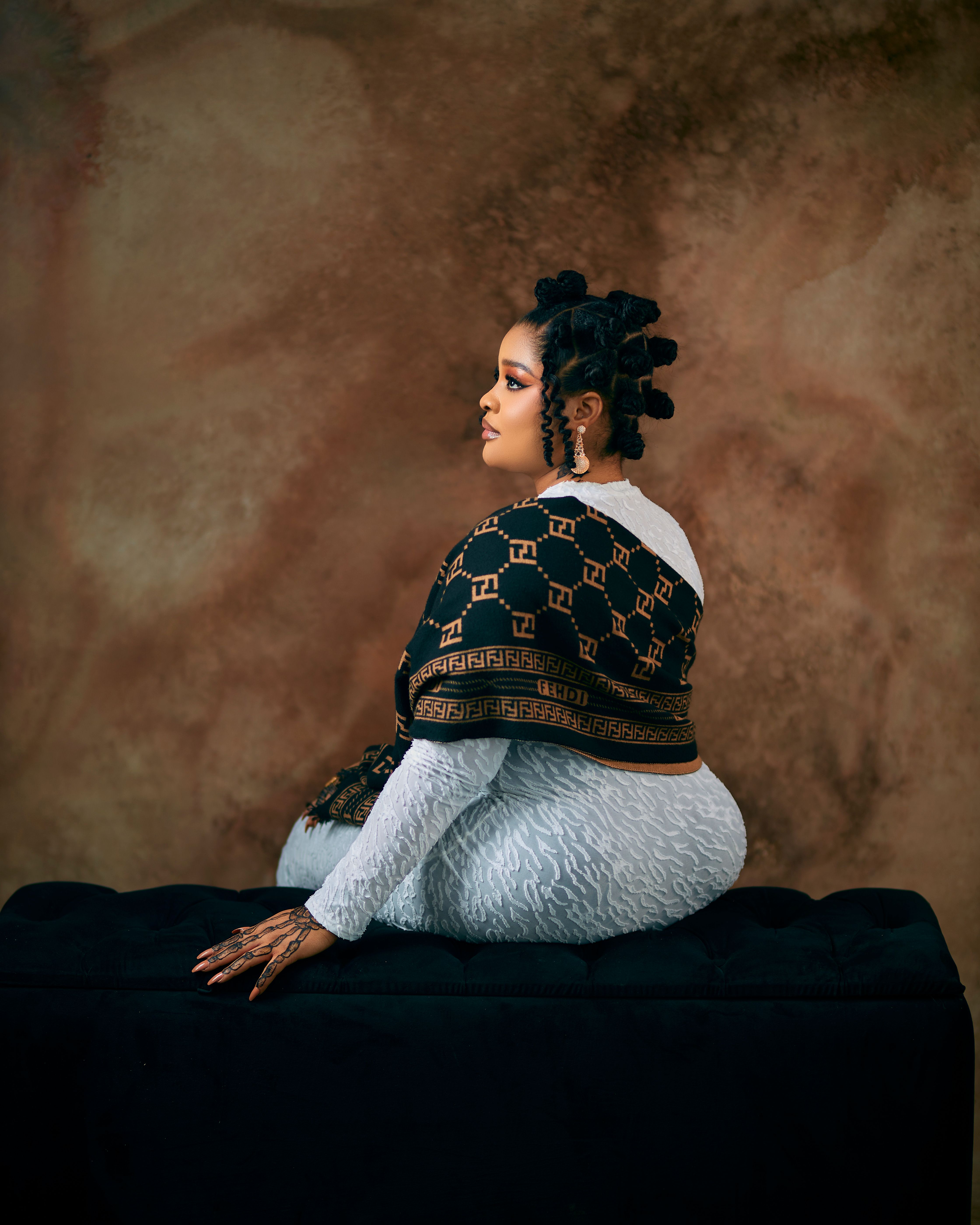 Side profile portrait of a woman in stylish attire against a textured background, exuding elegance.