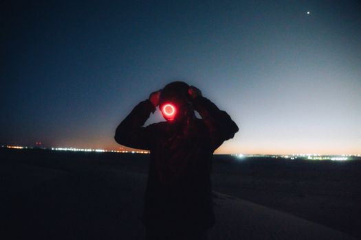 Silhouette with glowing mask in the Algerian desert under a starry night sky. Futuristic and mysterious vibe.