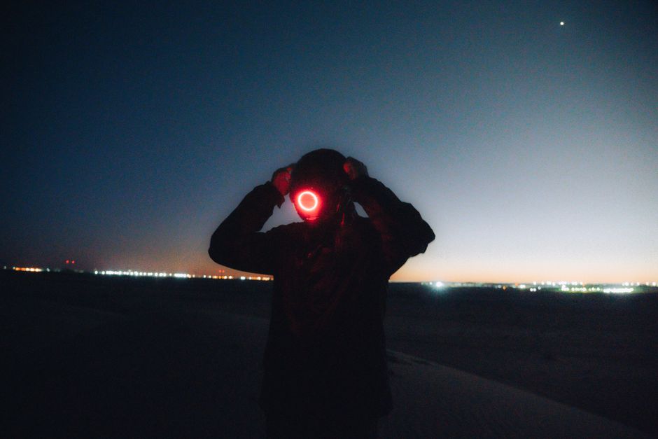 Silhouette with glowing mask in the Algerian desert under a starry night sky. Futuristic and mysterious vibe.