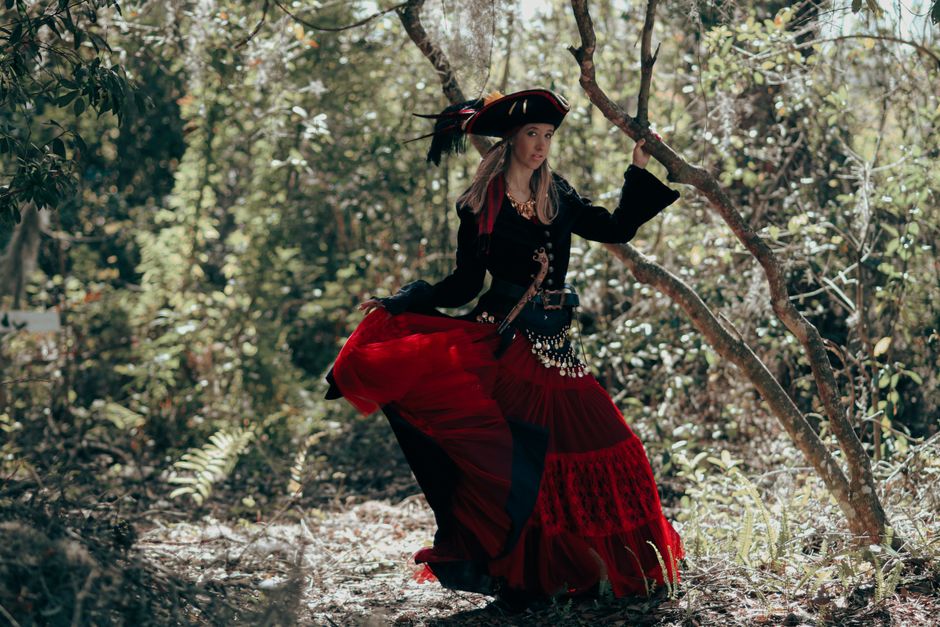 A woman dressed as a pirate in a forest, showcasing a blend of adventure and mystique.