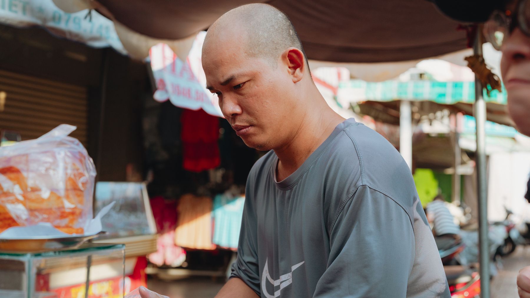A street vendor prepares food at a bustling outdoor market in Bình Thuận, Vietnam.
