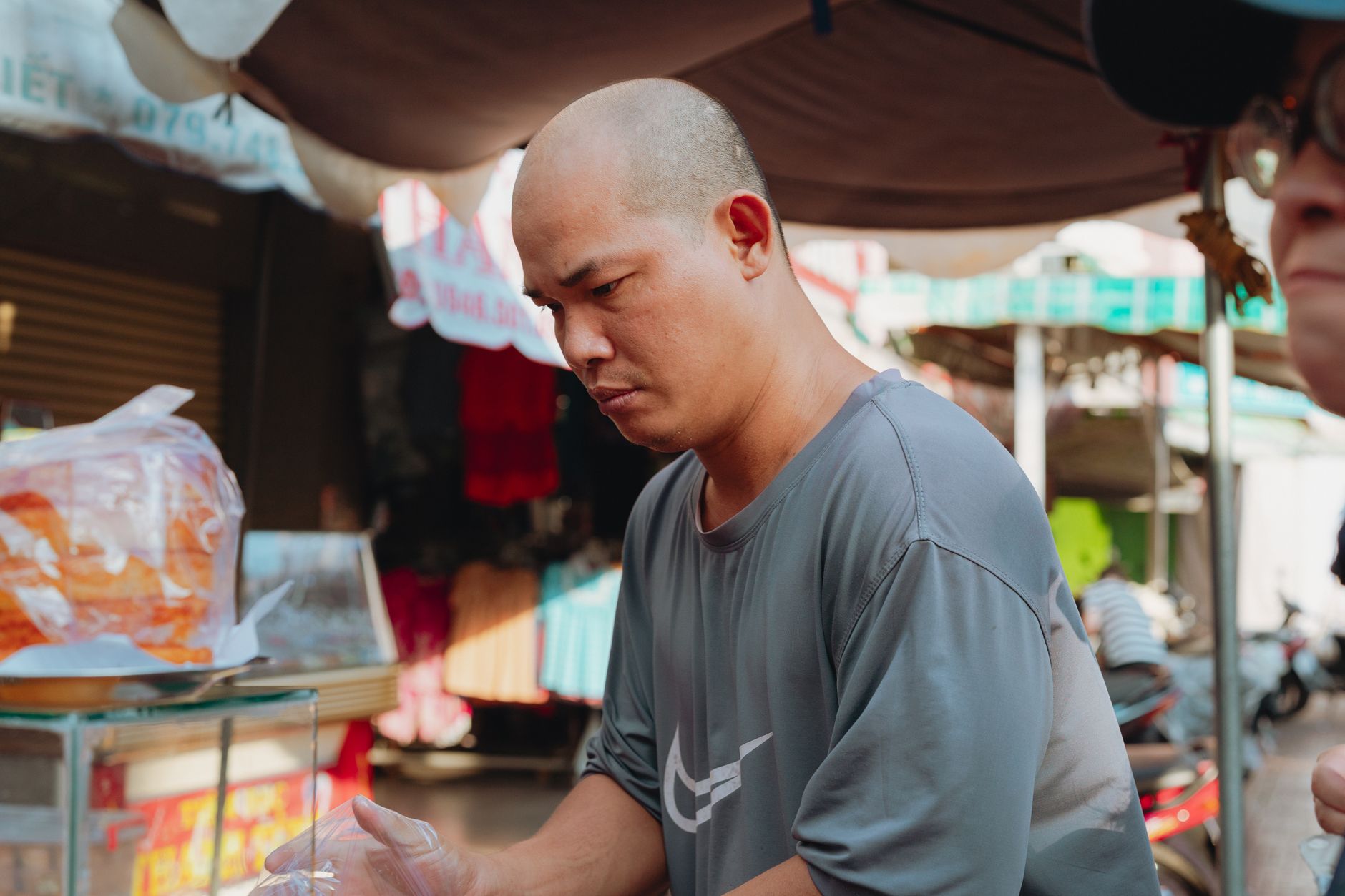 A street vendor prepares food at a bustling outdoor market in Bình Thuận, Vietnam.